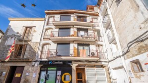 Un immeuble à plusieurs étages doté de balcons, une agence de la banque CaixaBank et une porte verte.