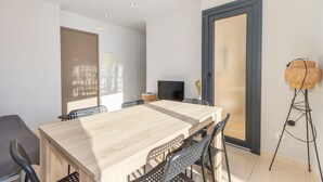Une pièce moderne avec une table à manger en bois, des chaises noires, un téléviseur et un lampadaire.