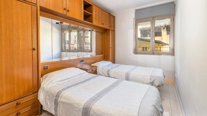 Une chambre avec deux lits, une armoire en bois et une fenêtre donnant sur un beau paysage.