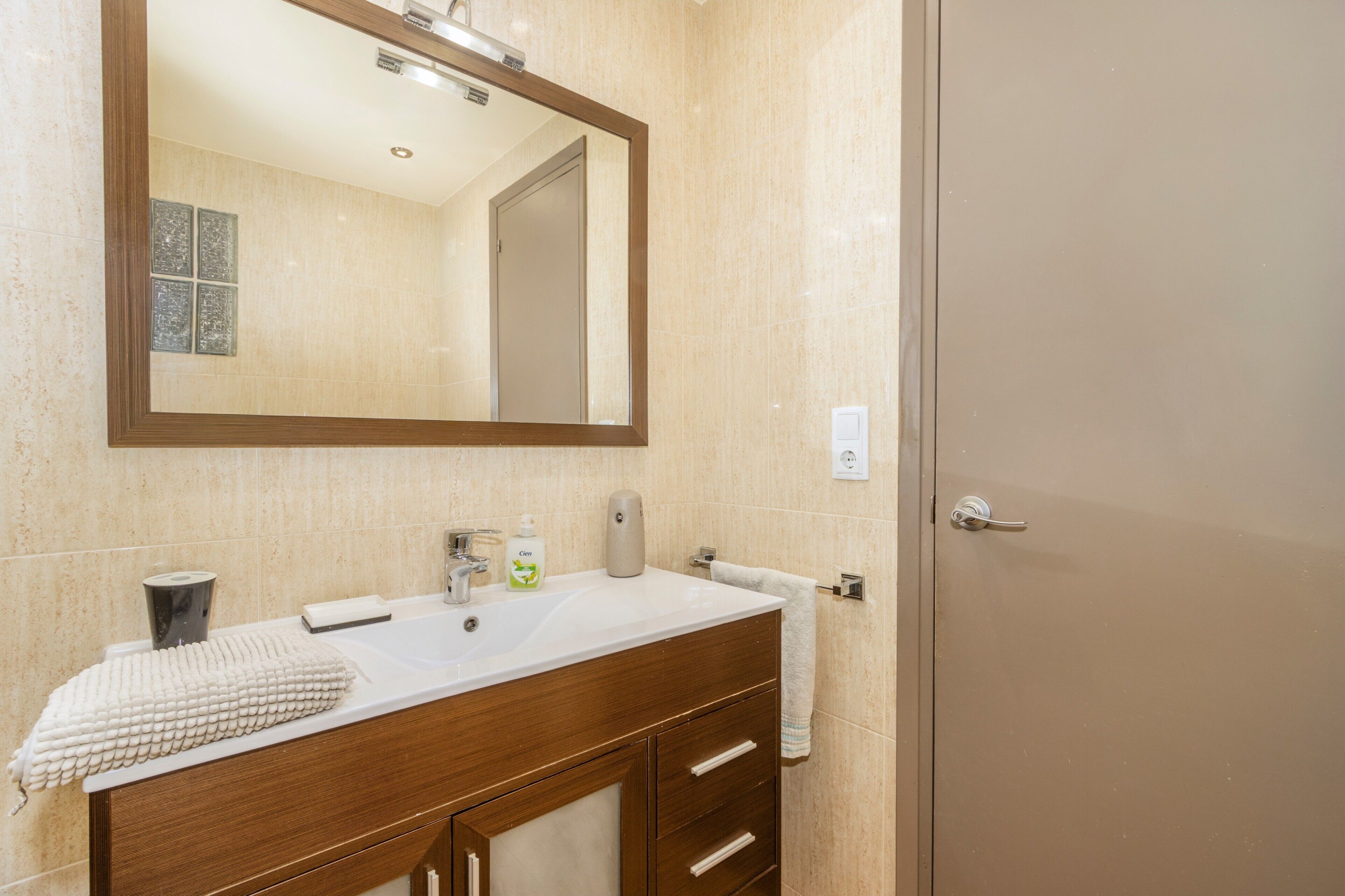 Un bagno con lavandino, specchio, asciugamano e articoli da toilette.