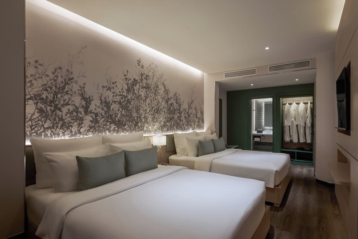 A hotel room with two beds, a large wall mural, a walk-in closet, and a TV.