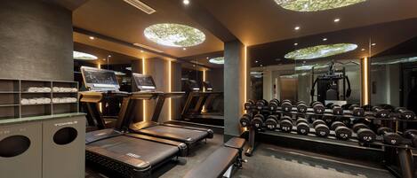 A gym with treadmills, dumbbells, and a bench.