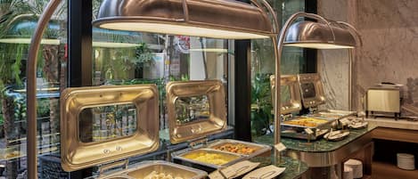 Montaje de bufé con varias estaciones de comida, incluyendo una sección para dumplings y otra para un plato llamado 'Shumali'.