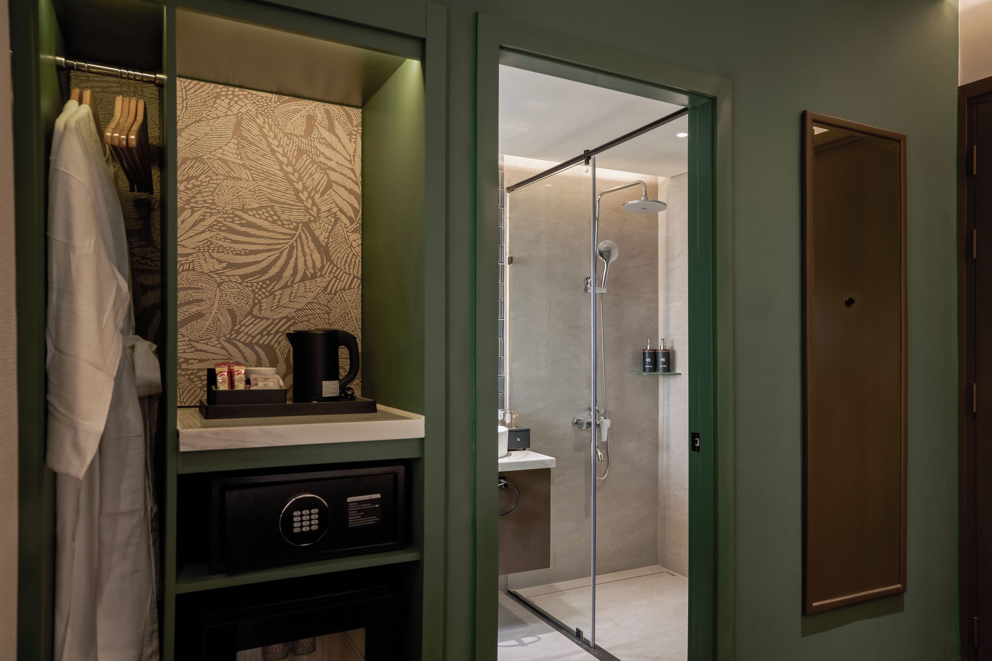 A modern bathroom with a glass shower enclosure, a vanity with a patterned mirror, and a robe hanging on a rack.