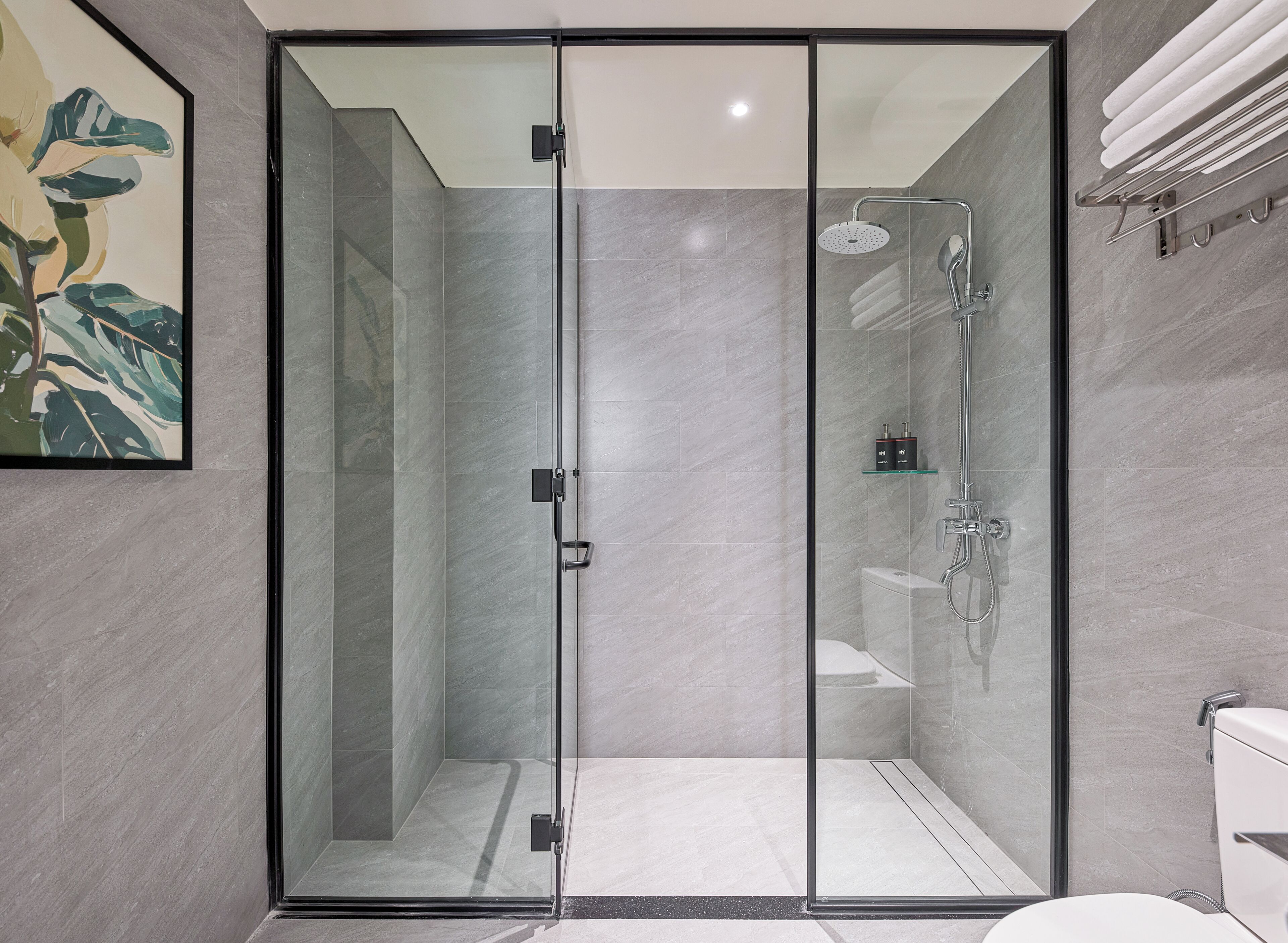 A modern bathroom with a glass-enclosed shower, a glass door, and a marble floor.