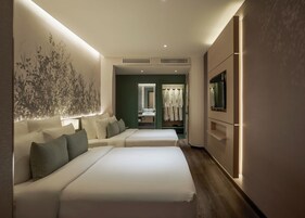 A hotel room with two beds, a large wall art, a mirror, a wardrobe, and a TV.