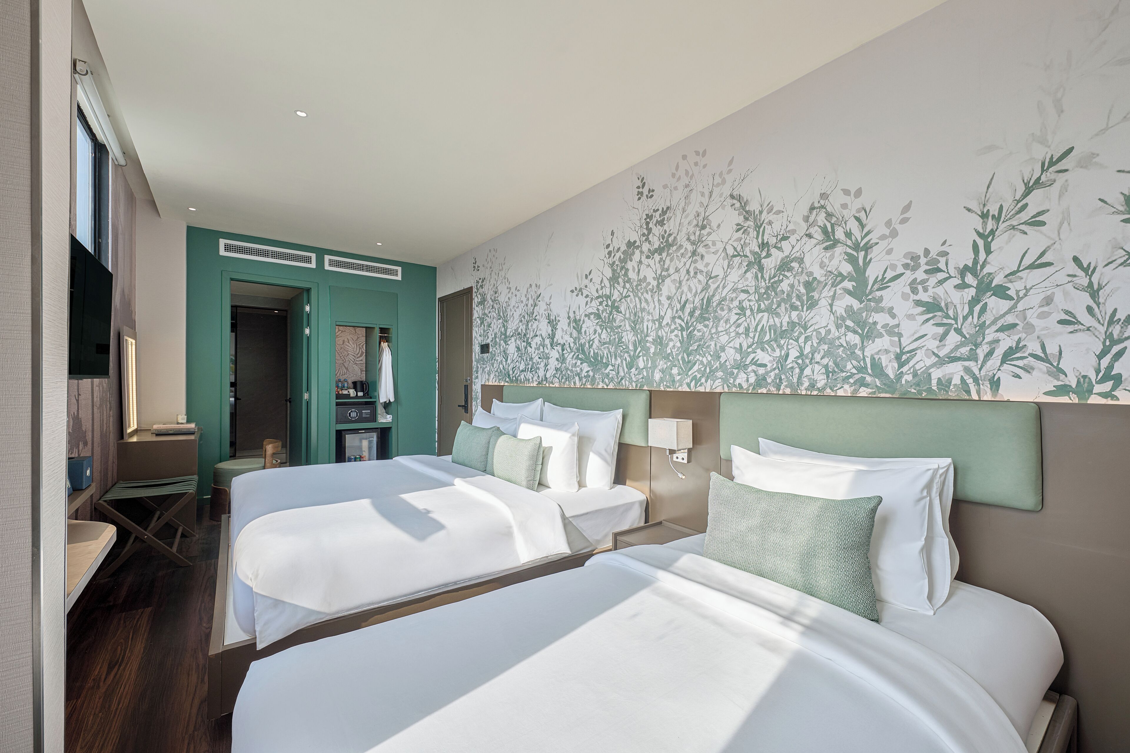 A hotel room with two beds, a TV, a desk, and a bathroom.