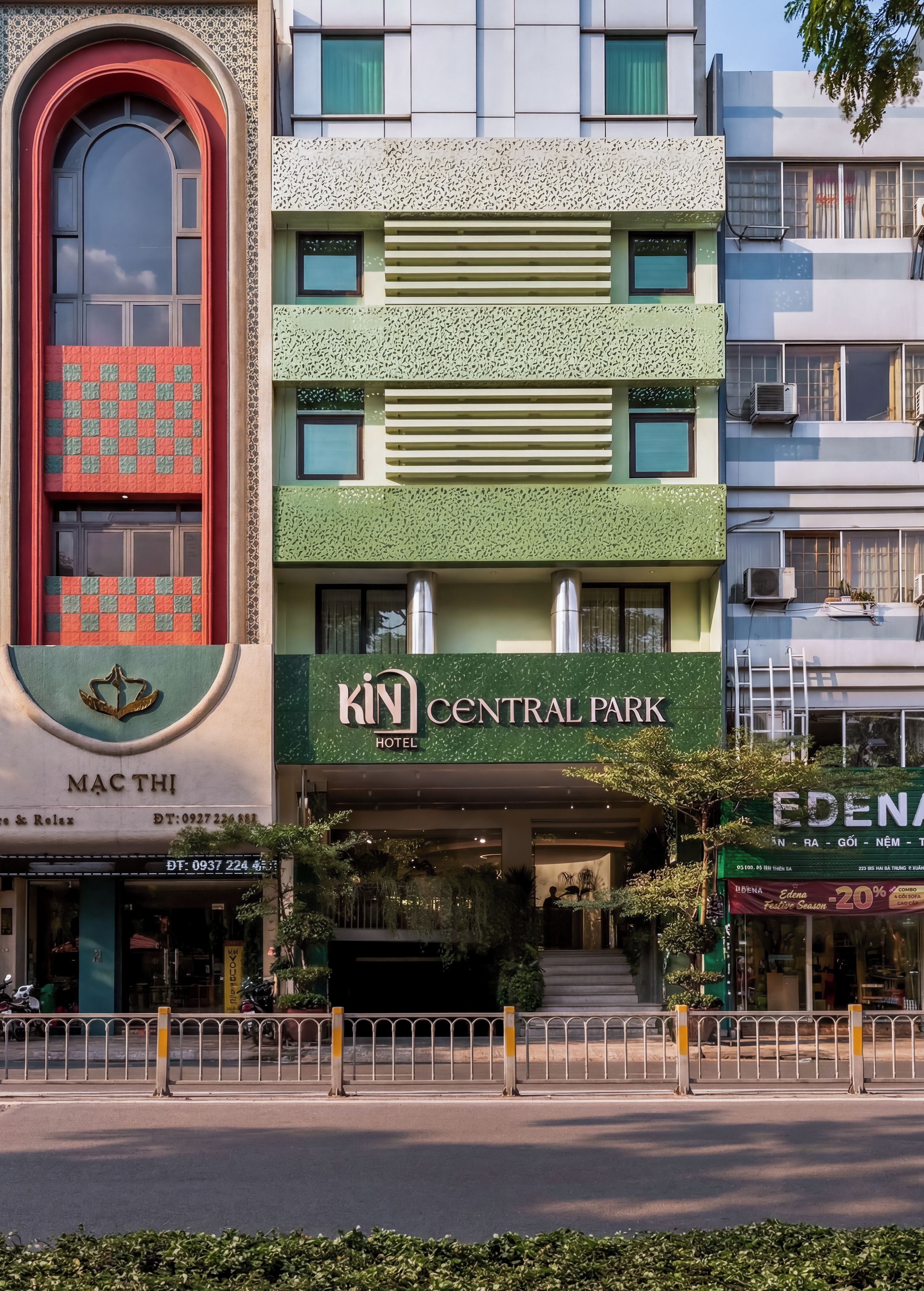 Un hotel de varios pisos con fachada verde, entrada central y nombre de marca visible.