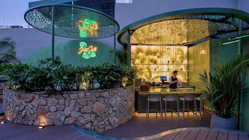An outdoor bar area with a stone wall, wooden deck, and tropical plants.