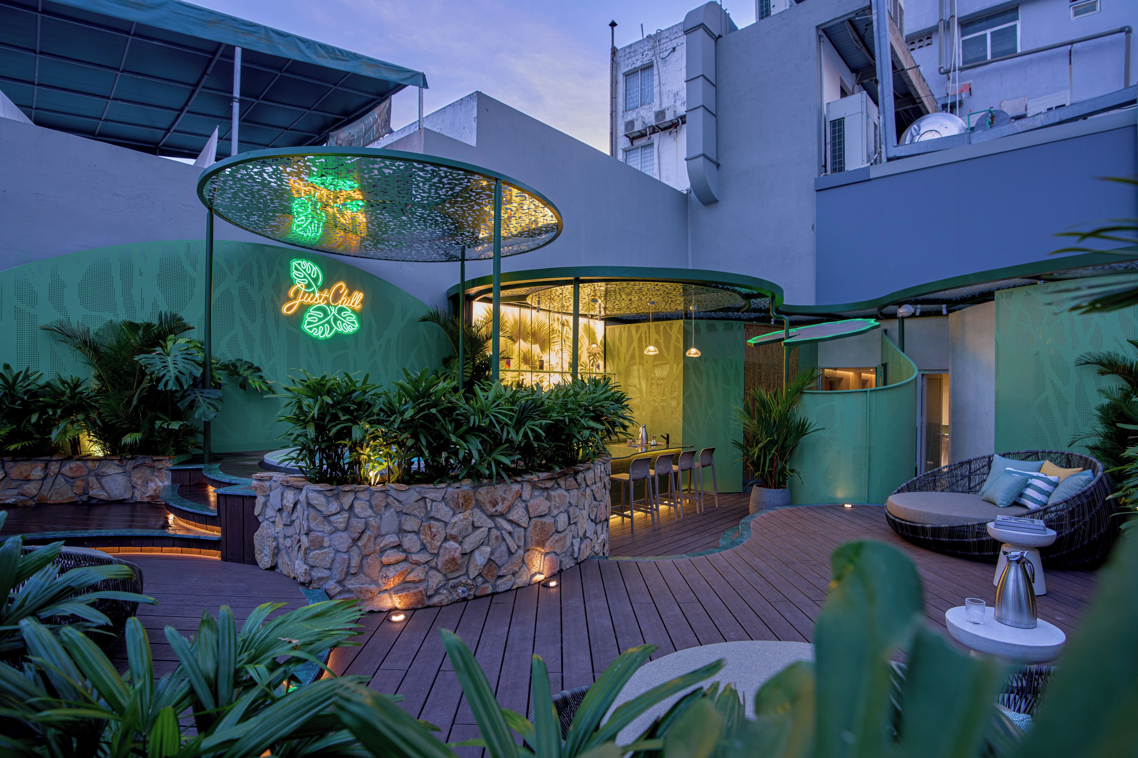 An outdoor bar area with a stone wall, seating, and a neon sign.