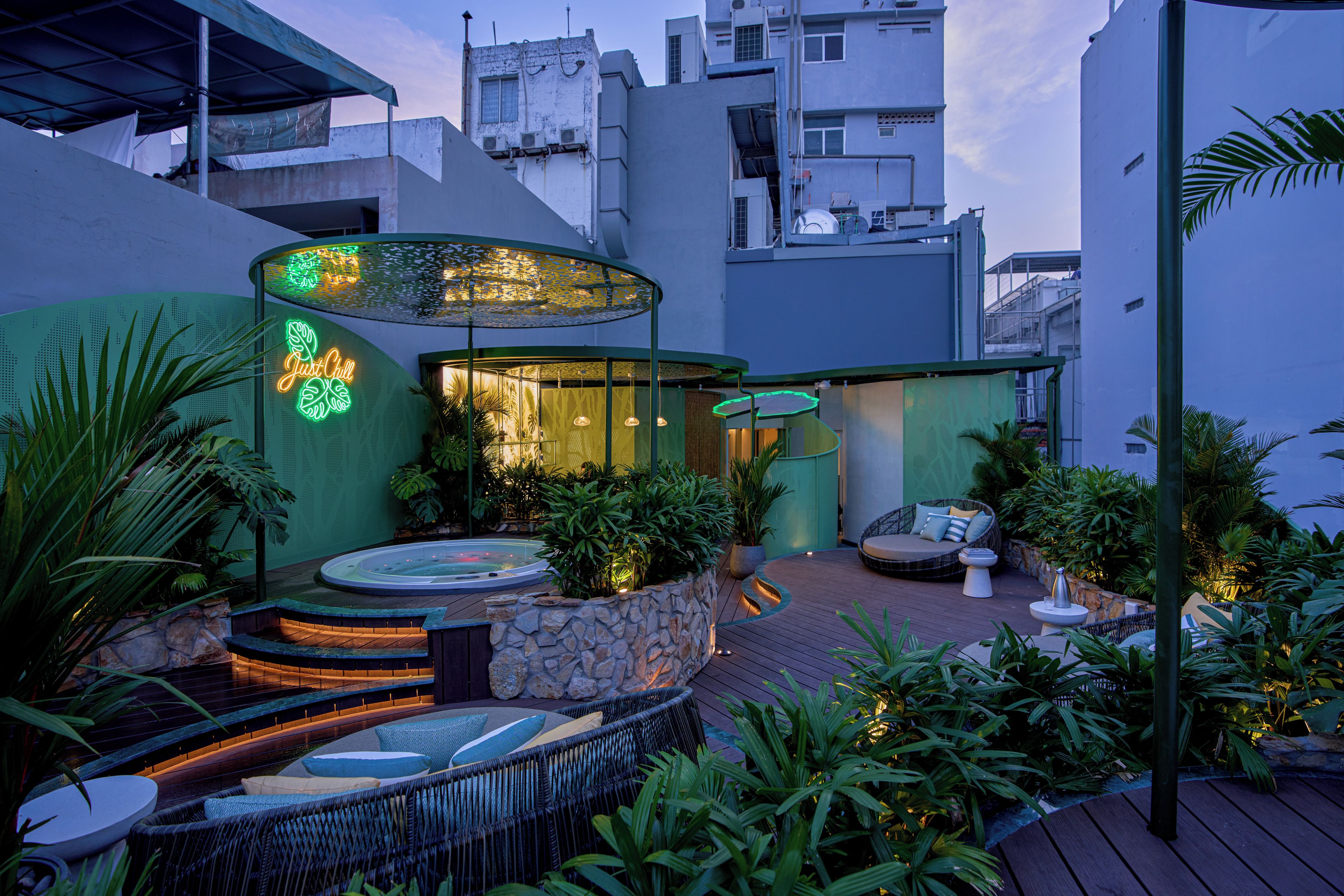 Un jardin sur le toit équipé d'un jacuzzi, d'un espace salon et d'une enseigne lumineuse au néon.