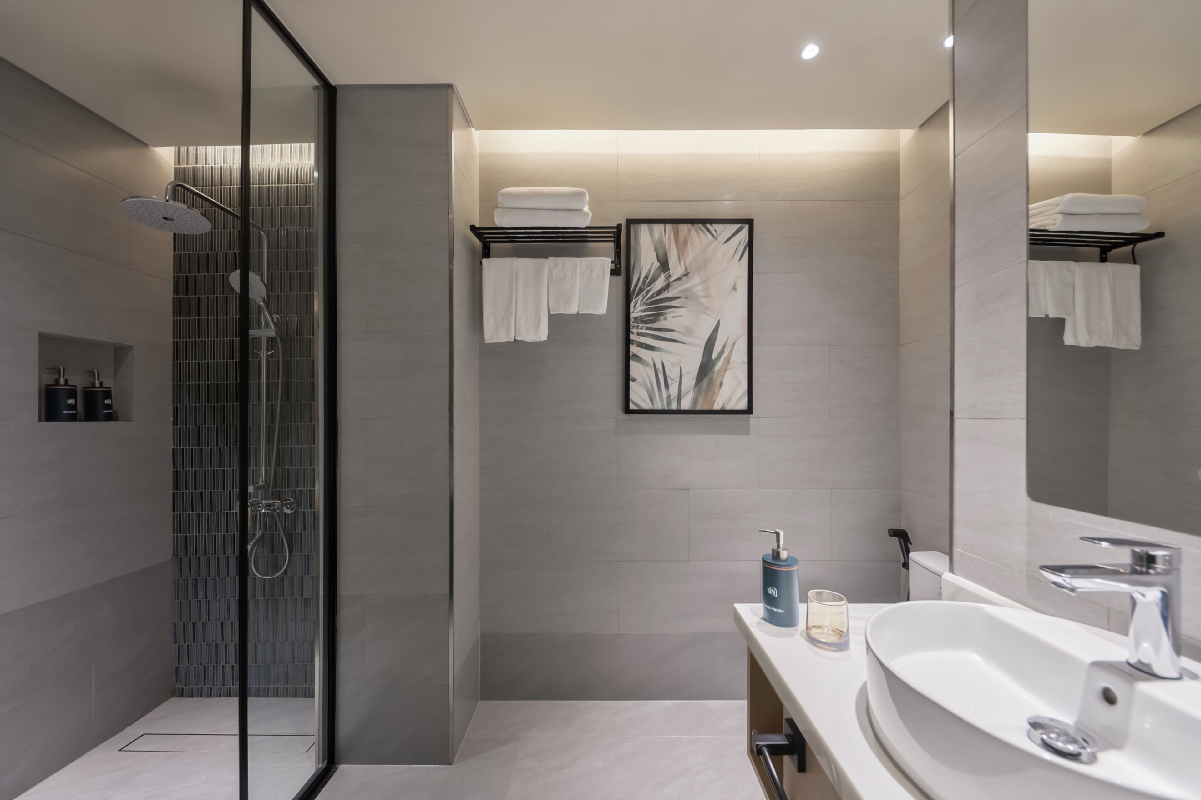 A modern bathroom with a glass-enclosed shower, a large mirror, and a white sink.
