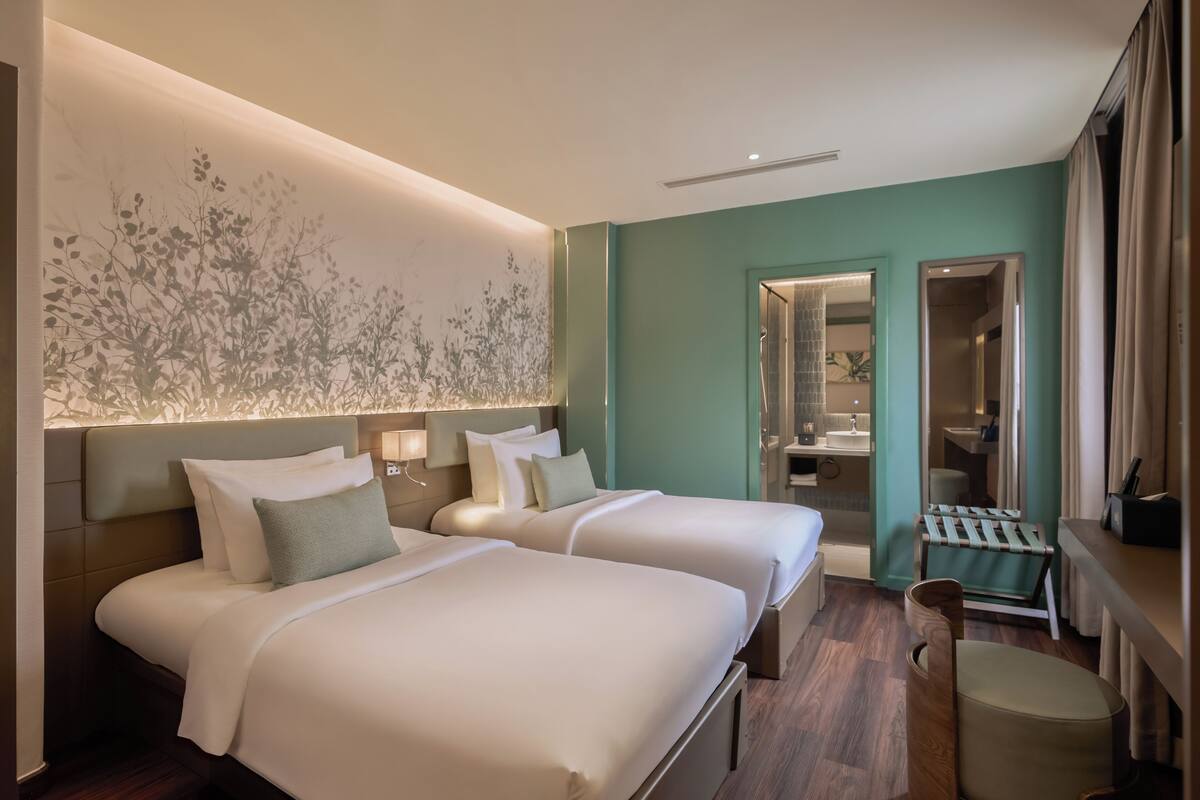 A hotel room with two beds, a large mirror, a vanity, and a small seating area.