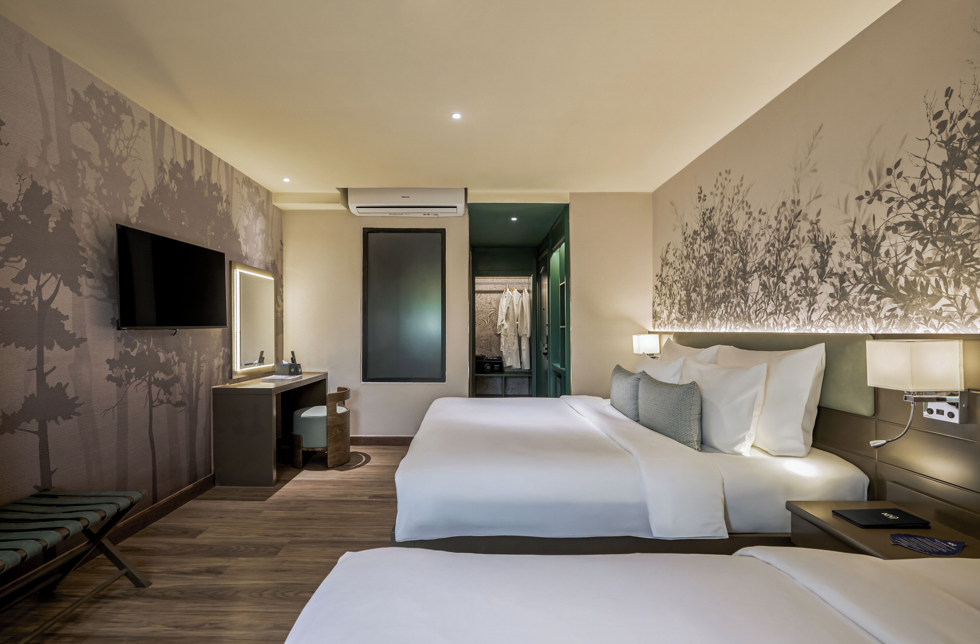 A hotel room with a bed, a desk, a TV, and a bathroom visible through an open door.