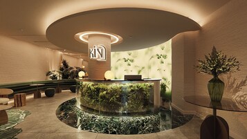 A reception area with a curved desk, a large aquarium, and a wall with a leafy pattern.