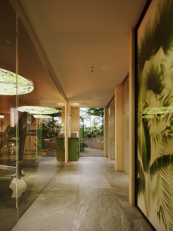 A corridor with a glass wall on one side, a green wall with plants on the other, and a ceiling with recessed lighting. - KiN Hotel Central Park (Ho Chi Minh City)