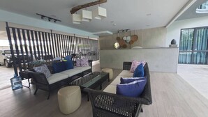 A modern lounge area with wicker furniture, a wooden partition, and a bar area with a unique ceiling design. - Stylish Bang Saray Apartment With Pool and Resort Facilities (Sattahip)