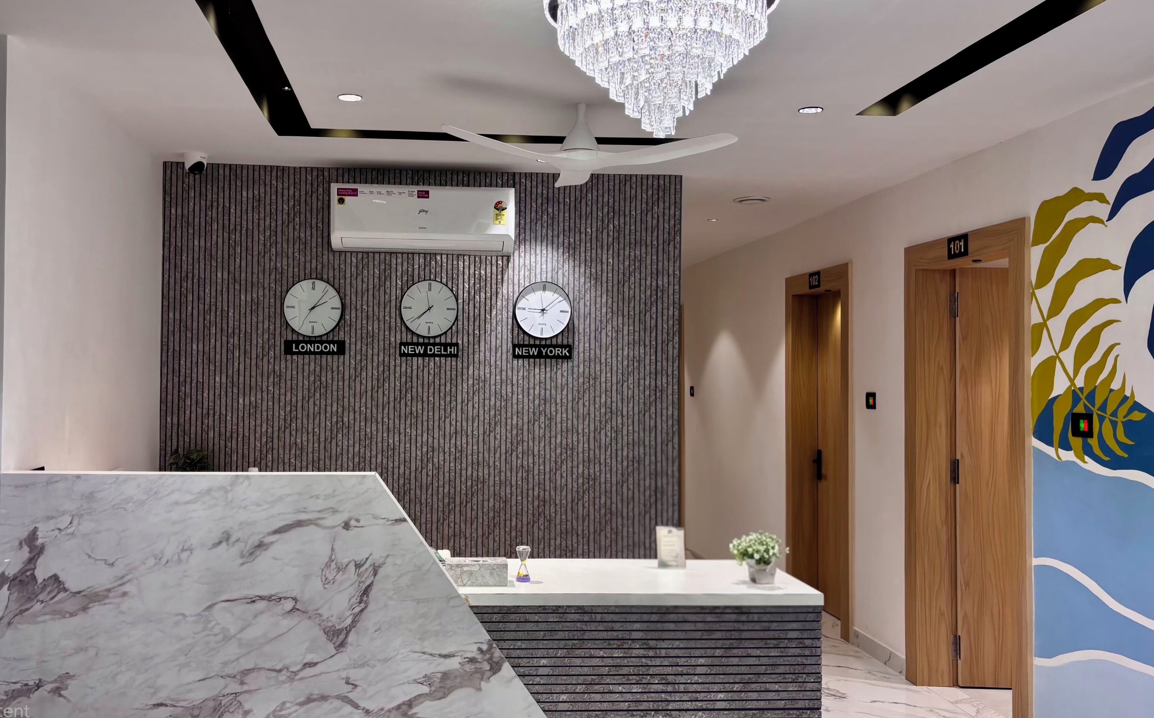 A reception area with a marble counter, a chandelier, and clocks indicating different time zones.