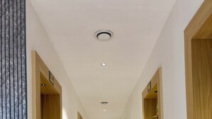 Pasillo de hotel con suelo de mármol, puertas de madera y un letrero de 'prohibido el acceso'.