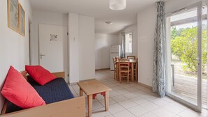 A modern living room with a sofa, a dining table, and a kitchen area. - Cottage for 6 pers in a residence with pool (Ondres)