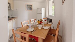Cocina compacta con una mesa de comedor, sillas, un refrigerador y una ventana.