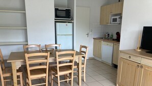 A compact kitchen with a dining table, chairs, a microwave, a refrigerator, and a dishwasher. - apartment, balcony, view of nature, sleeps 6 (Ondres)