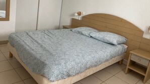 A bedroom with a bed, a nightstand, a wall-mounted lamp, and a framed picture. - apartment, balcony, view of nature, sleeps 6 (Ondres)