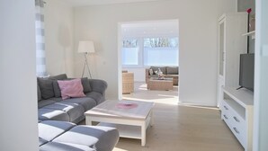 A modern living room with a grey sofa, a white coffee table, and a TV stand. - Top modern vacation apartment 90 m² in a central location in Grömitz. (Grömitz)