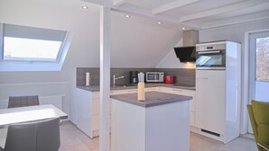 Ett modernt kök med en central köksö, inbyggda vitvaror och ett takfönster.
