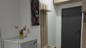 A compact kitchen with a white refrigerator, a wooden cabinet above the sink, and a door with a handle. - Snowy Loft Didveli (Bakuriani)