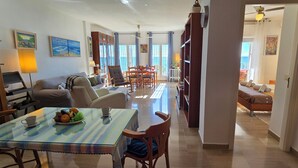 Zona d'estar àmplia amb taula de dinar preparada per a dues persones, sofà i prestatges.