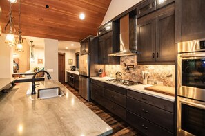 Une cuisine moderne avec des meubles en bois foncé, des appareils électroménagers en acier inoxydable et un plan de travail en marbre.