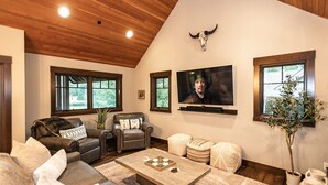 Un salón amplio con techo alto, sofás de cuero, una mesa de centro y un televisor de pared.