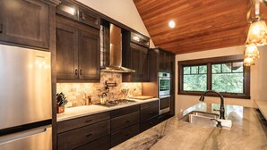 Una cocina moderna con armarios de madera oscura, electrodomésticos de acero inoxidable y una isla grande con pileta.