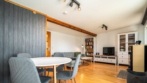 A modern living room with a dining area, wooden flooring, a bookshelf, a television, and a cabinet. - "Waterkieker" Vacation Home on Lake Jabelschen with a Dock & Outdoor Sauna (Jabel)