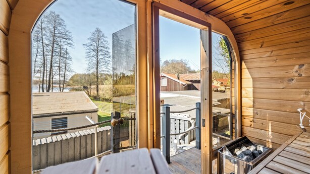 A wooden deck with a view of a building and trees. - "Waterkieker" Vacation Home on Lake Jabelschen with a Dock & Outdoor Sauna (Jabel)