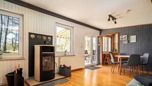 A room with a fireplace, wooden flooring, a dining area with chairs, and a view through a glass door. - "Waterkieker" Vacation Home on Lake Jabelschen with a Dock & Outdoor Sauna (Jabel)
