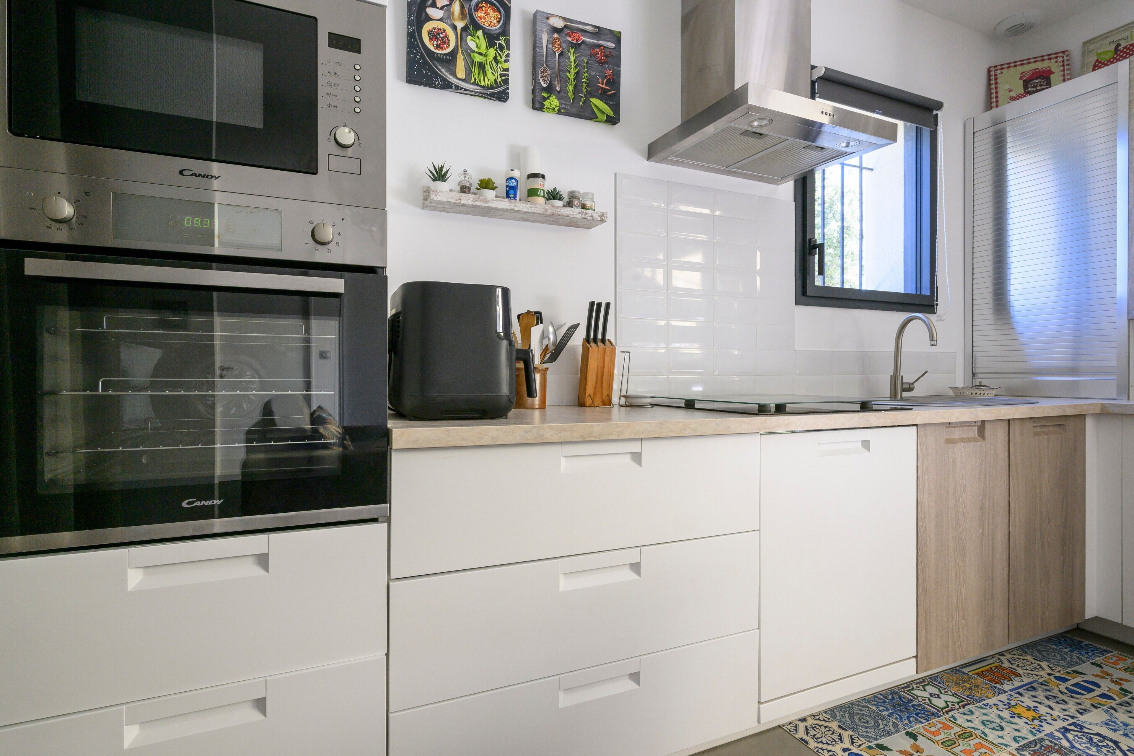 Una cucina moderna con forno integrato, microonde e macchina da caffè sul piano di lavoro.