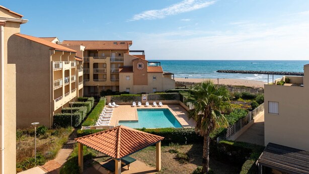 Ein Resort mit Pool, Blick auf den Strand und mehreren Balkonen.