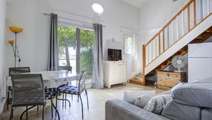 Ein geräumiger Wohnbereich mit Esstisch, Stühlen, einer Couch, einem Fernseher und einer Treppe.