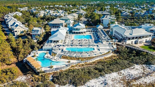 Vista aérea de un resort con una piscina grande, varios edificios y abundante vegetación.