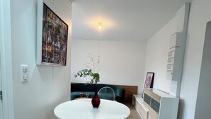 Una cocina moderna con una mesa redonda, sillas transparentes y un jarrón de flores.