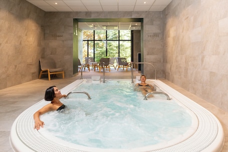 A spa area with a hot tub, seating, and a view through large windows.