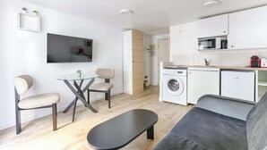 A modern apartment with a living area, kitchenette, and a washing machine. - Studio de charme au cœur du Sentier (Paris)