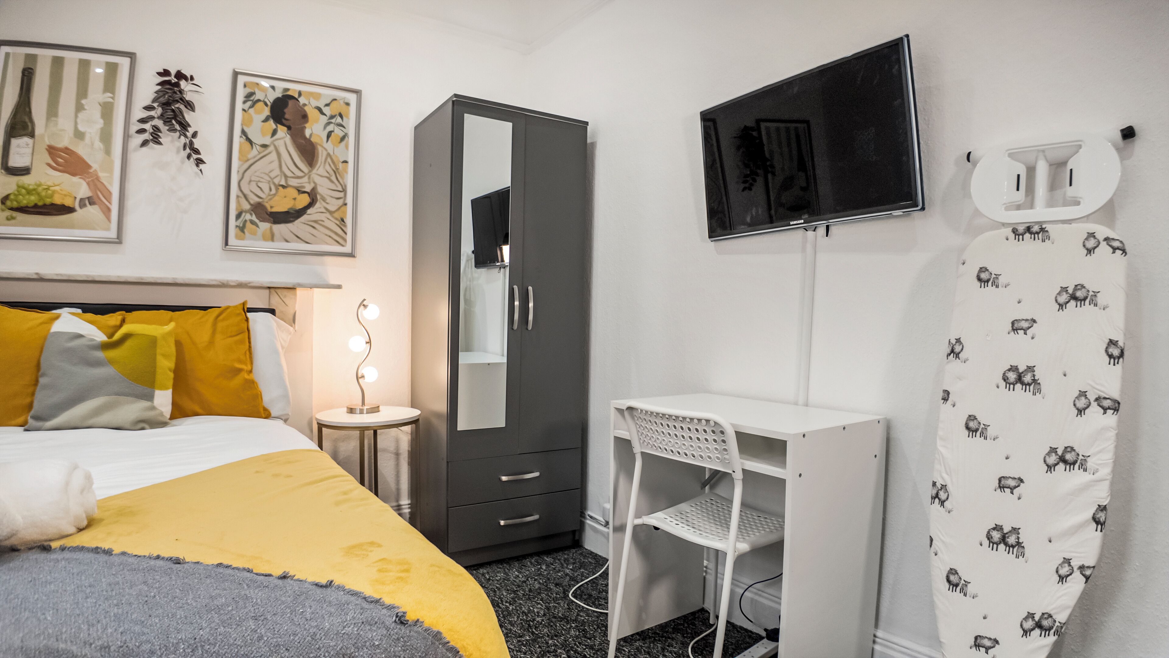 Ein Schlafzimmer mit Bett, Kleiderschrank, Schreibtisch, Fernseher und Duschvorhang.