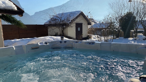 A hot tub in a snowy outdoor setting with a mountain in the background.