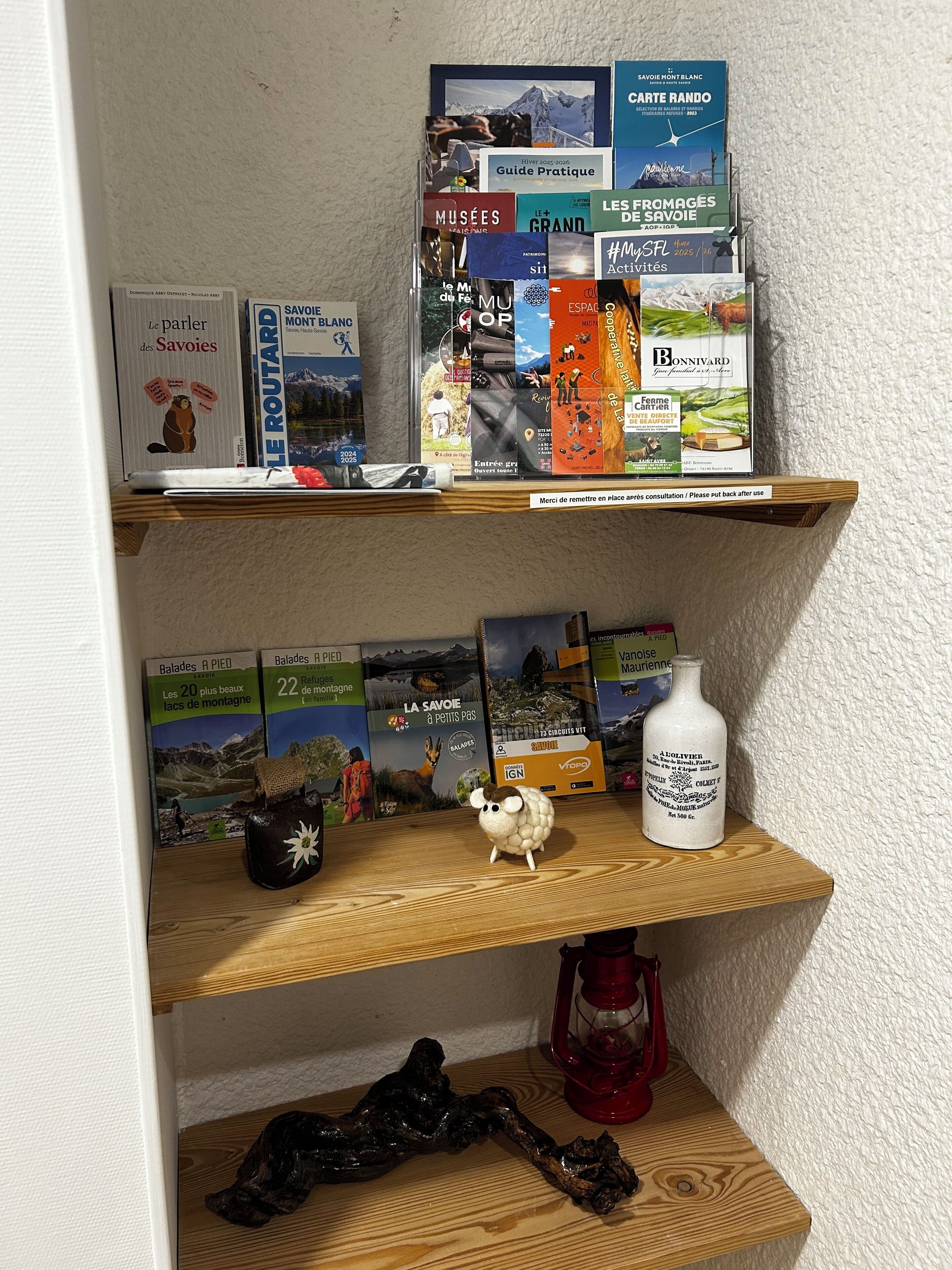 Een plank met reisboeken, een klein beeldje en een fles.