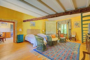 A room with a bed, two wicker chairs, a green chest of drawers, and a patterned rug. - Van Gogh - Sunny terrace overlooking the park (ARLES)