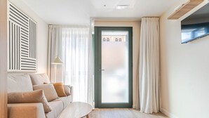 Una sala de estar moderna con un sofá, una mesita y una puerta que da al exterior.