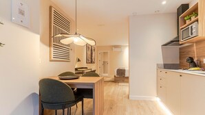 Una cocina moderna con armarios de madera, un comedor con mesa y sillas, y una lámpara colgante.